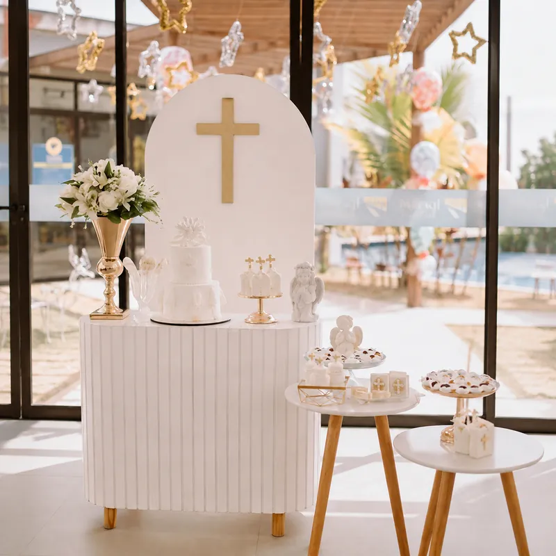 Mesa de batizado branca e dourada com bolo e docinhos personalizados